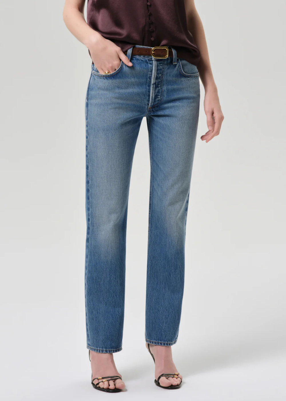 Person wearing blue jeans on a plain background