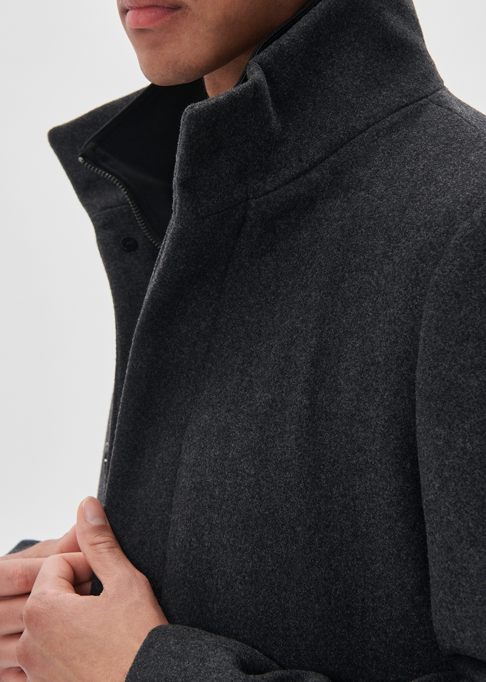 Close-up of a person wearing a dark gray coat on a light gray background