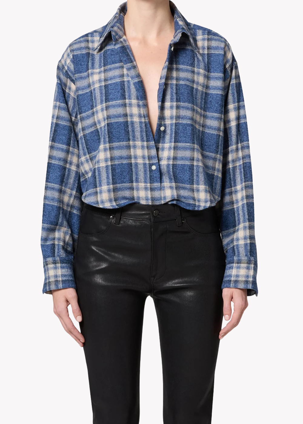 A model wearing a blue and white plaid button-down shirt tucked into black faux-leather pants, shown from the neck down against a light gray background.