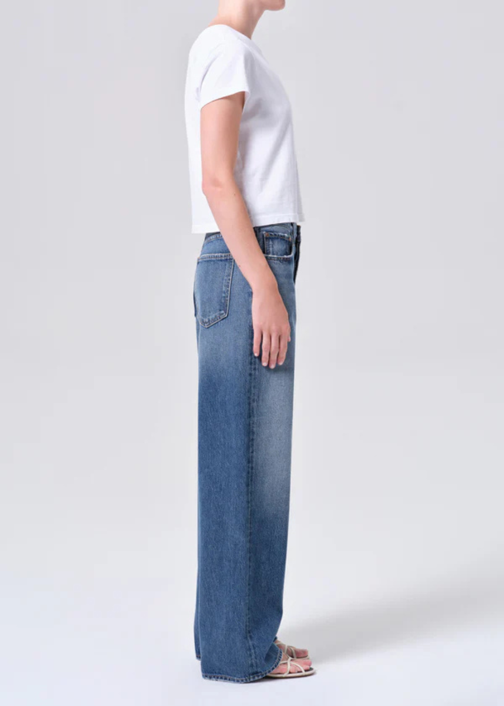 Person wearing a white t-shirt and blue jeans on a plain background