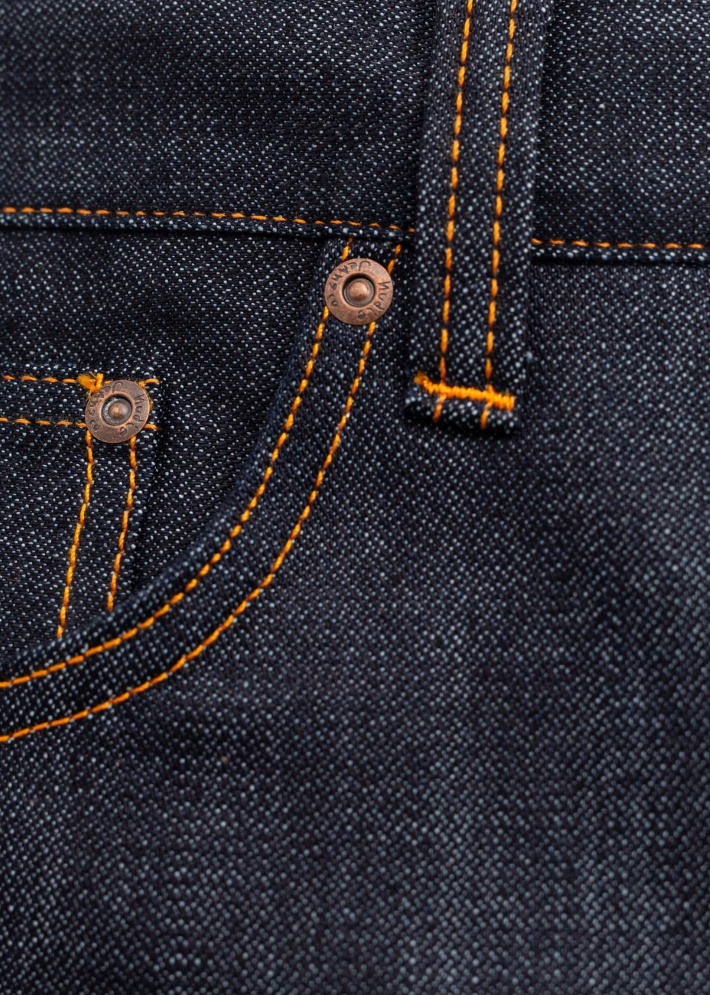 Close-up of dark indigo denim fabric with bright orange contrast stitching and a copper-toned metal rivet.