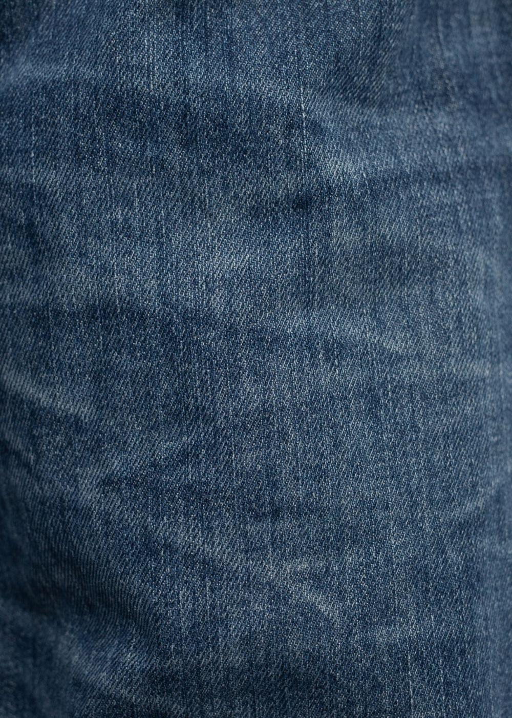 A close-up texture shot of dark blue denim fabric with visible weave and subtle fading.