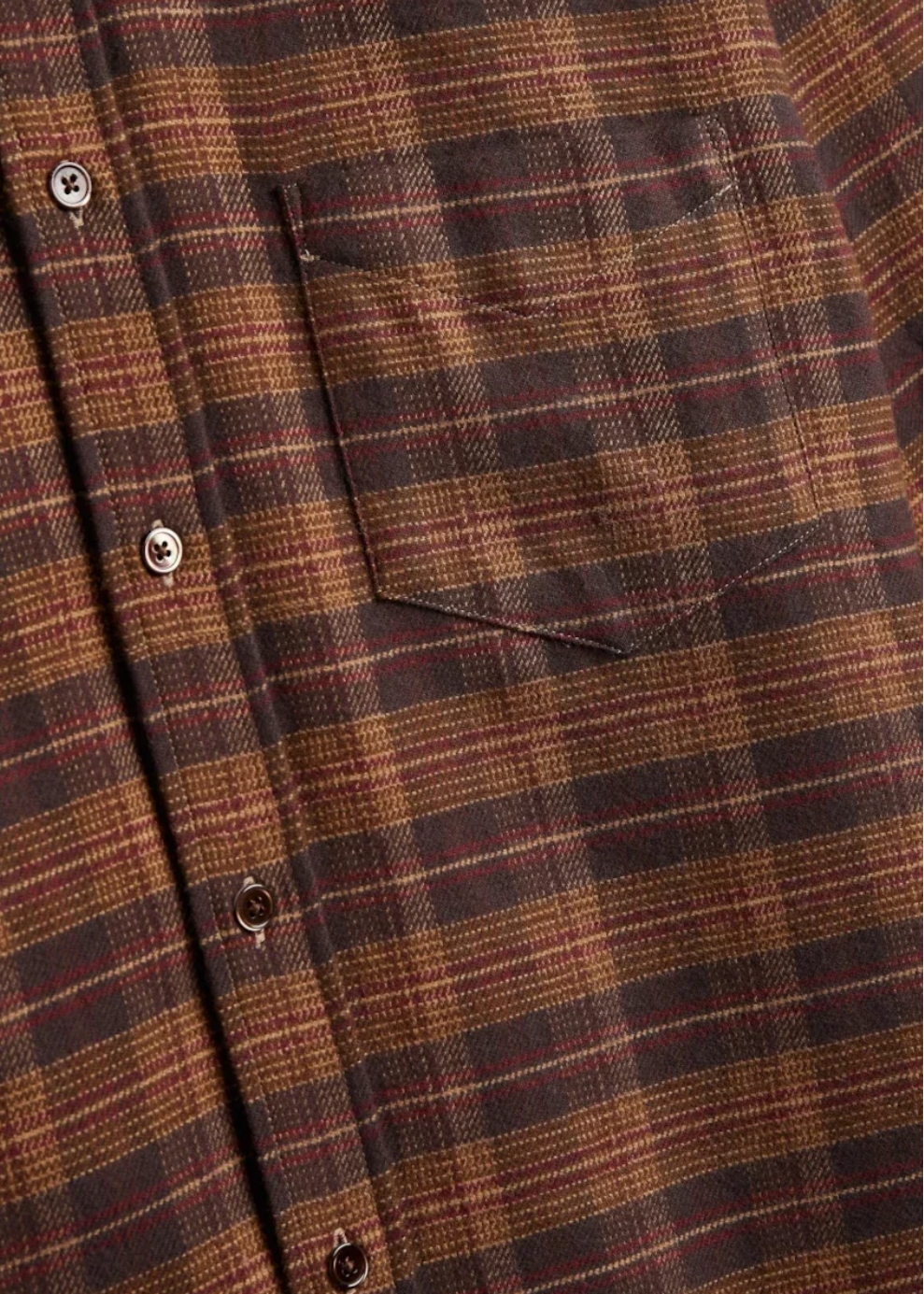 Close-up of a brown and dark red plaid button-up shirt with a chest pocket and metal buttons.