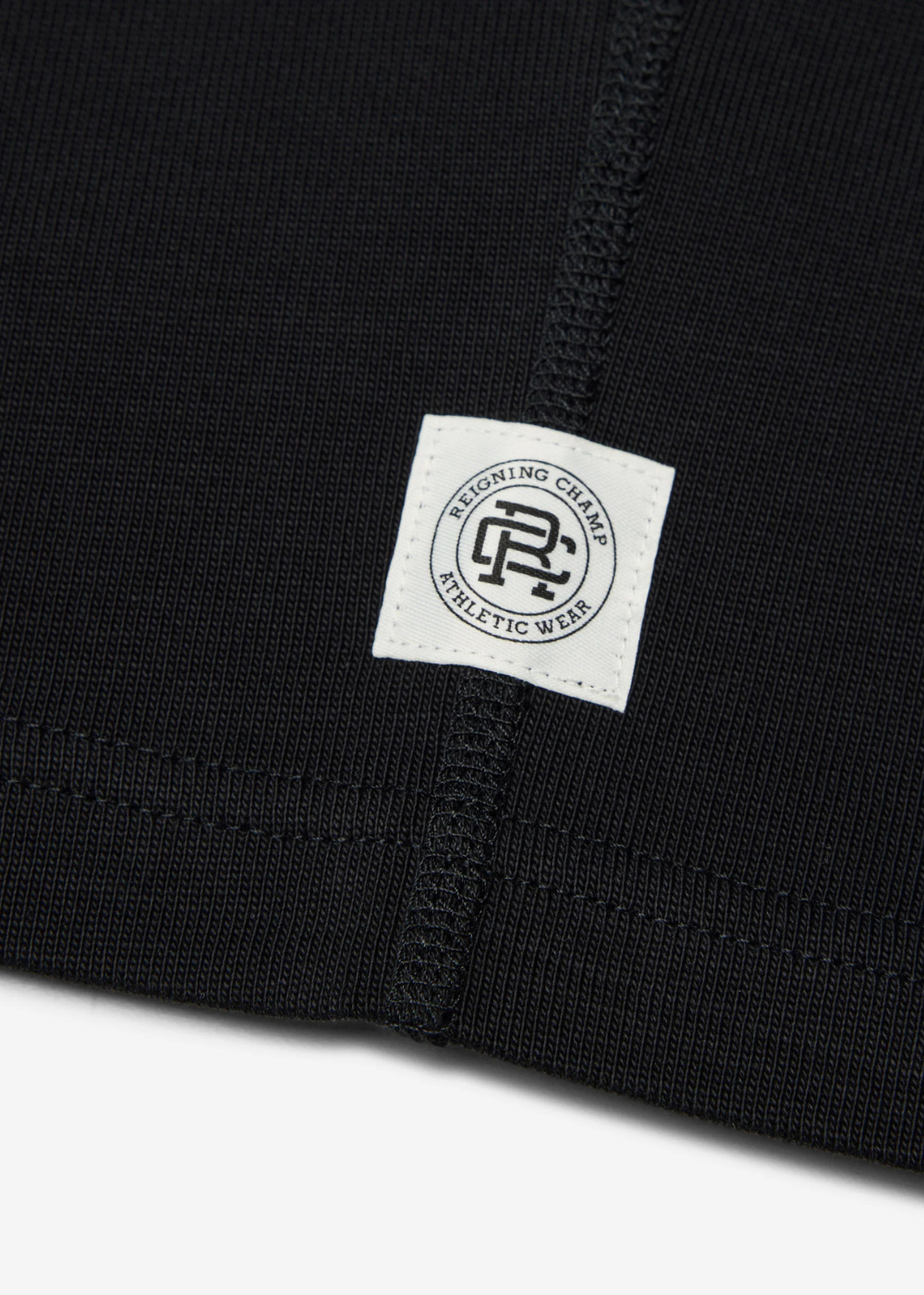 Navy blue athletic wear with a white label featuring a Reigning Champ logo and text.