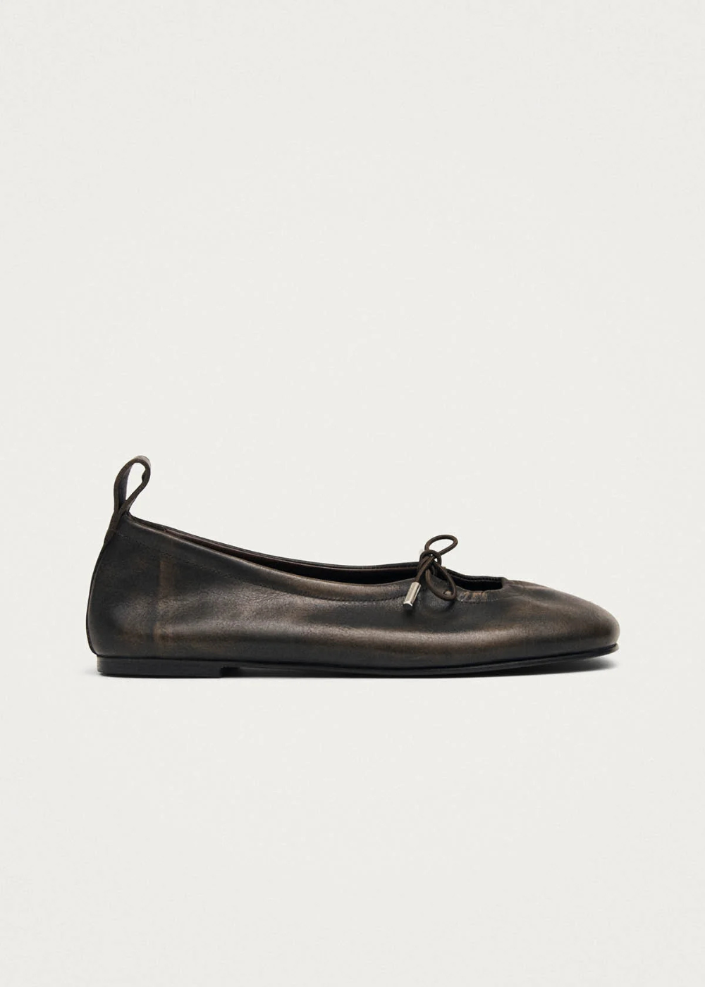 Black leather ballet flat shoe on a light gray background