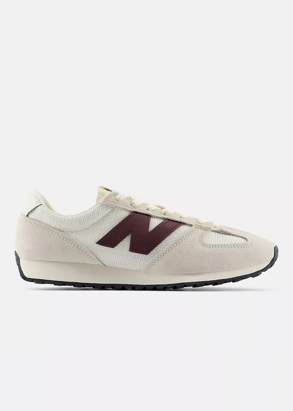 A New Balance sneaker in off-white suede and mesh with a dark burgundy 'N' logo on the side, shown in profile against a light gray background.