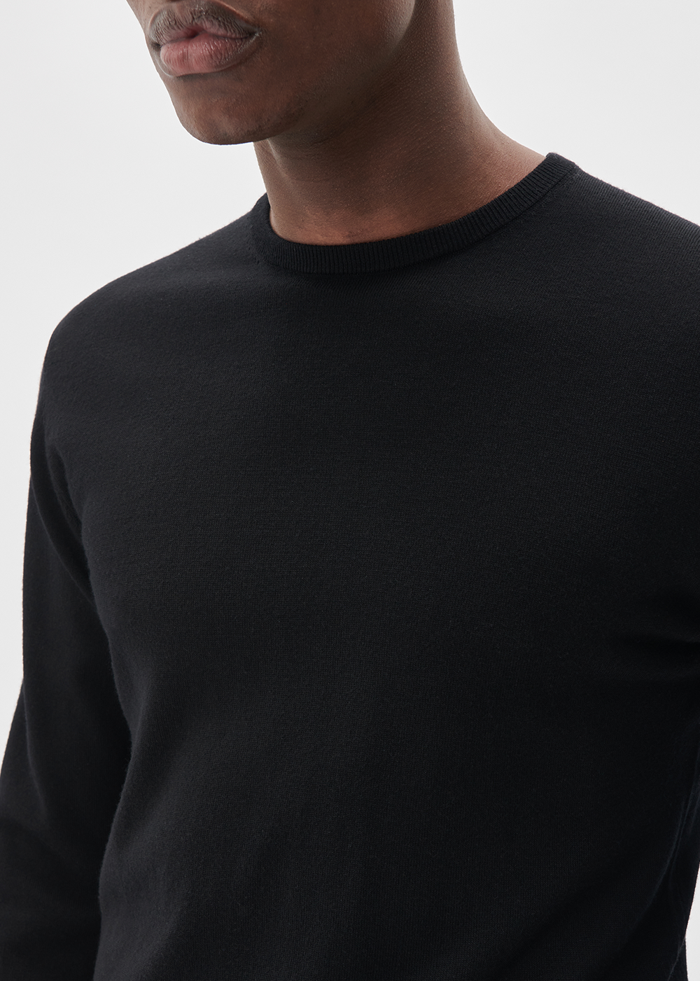Close-up of a person wearing a black long-sleeve shirt against a white background