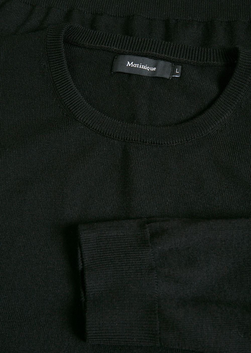 Close-up of a black sweater with a brand label on a dark background