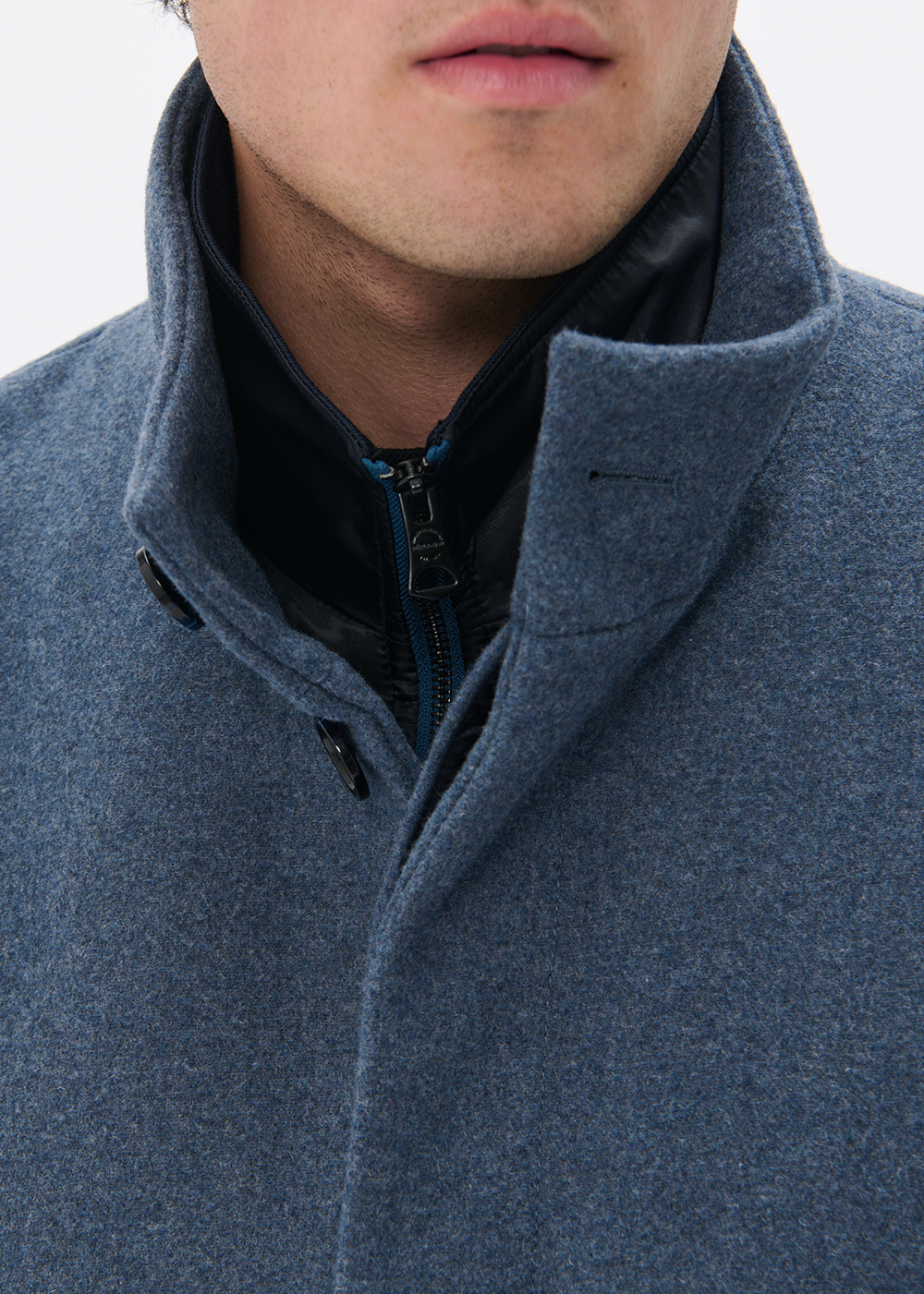 Close-up of a person wearing a blue coat with a gray background