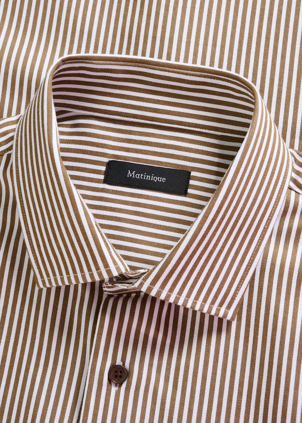Close-up of a collared button-up shirt with narrow vertical brown and beige stripes, featuring a black neck label that reads 'Matinique'.