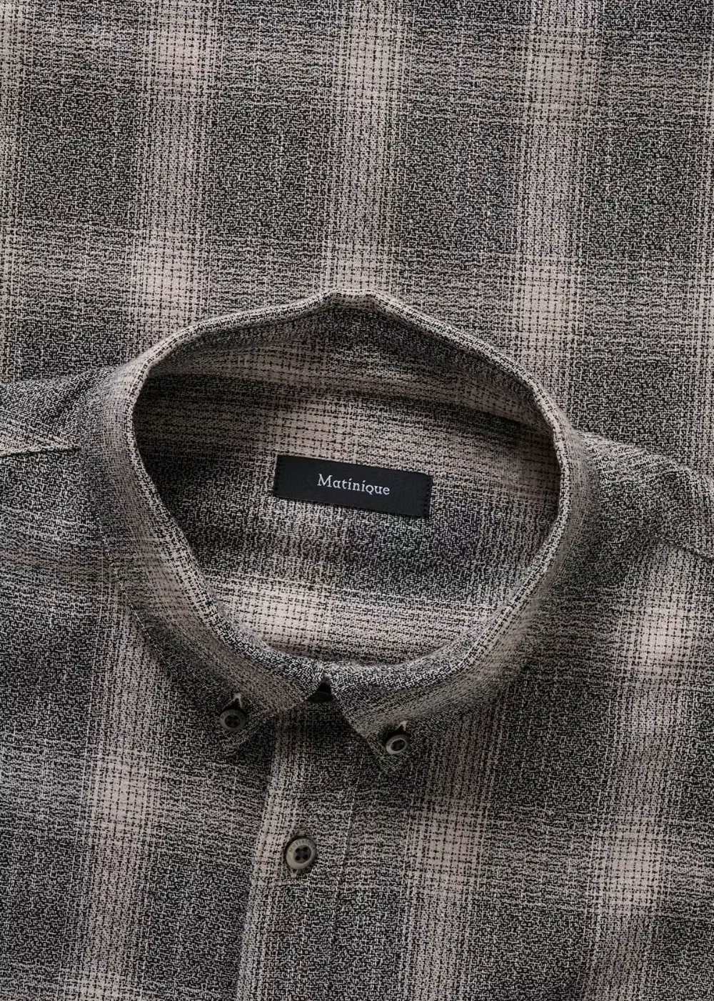 Close-up of a gray and beige plaid button-down shirt by Maitaine, showing the collar and front buttons.