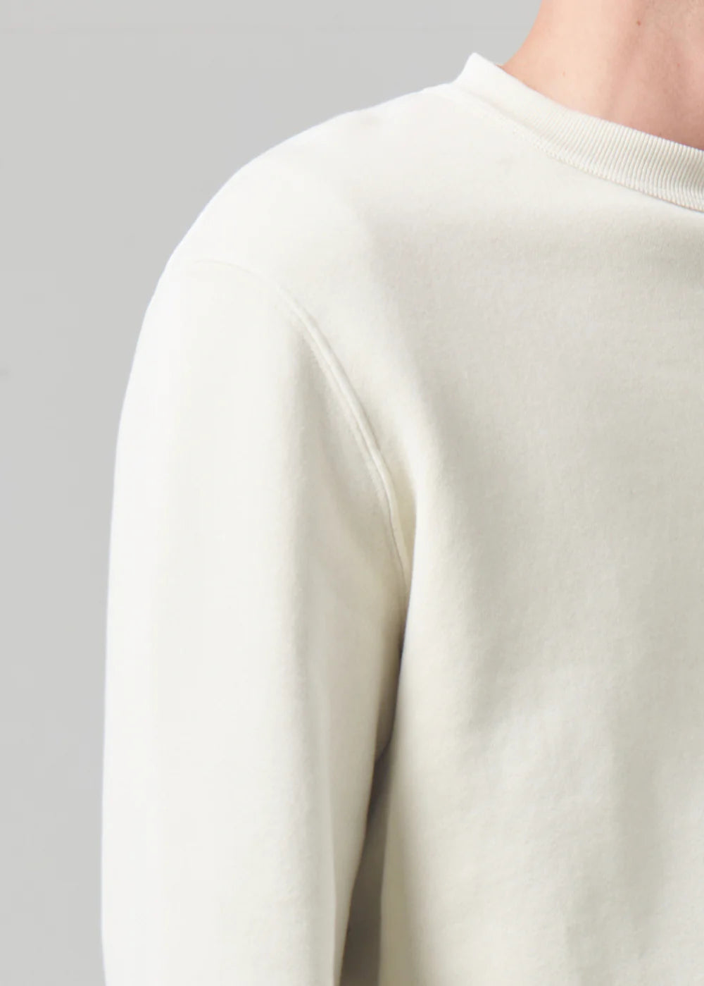 Close up, side view of a model wearing the Vintage crewneck sweater from Citizens of Humanity in off-white cream color