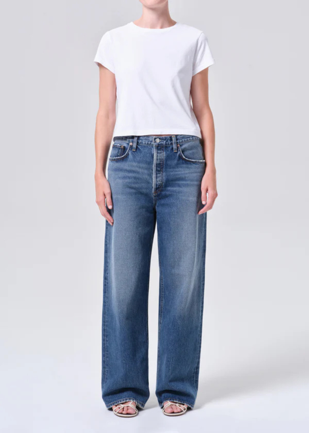 Person wearing a white t-shirt and blue jeans on a light gray background