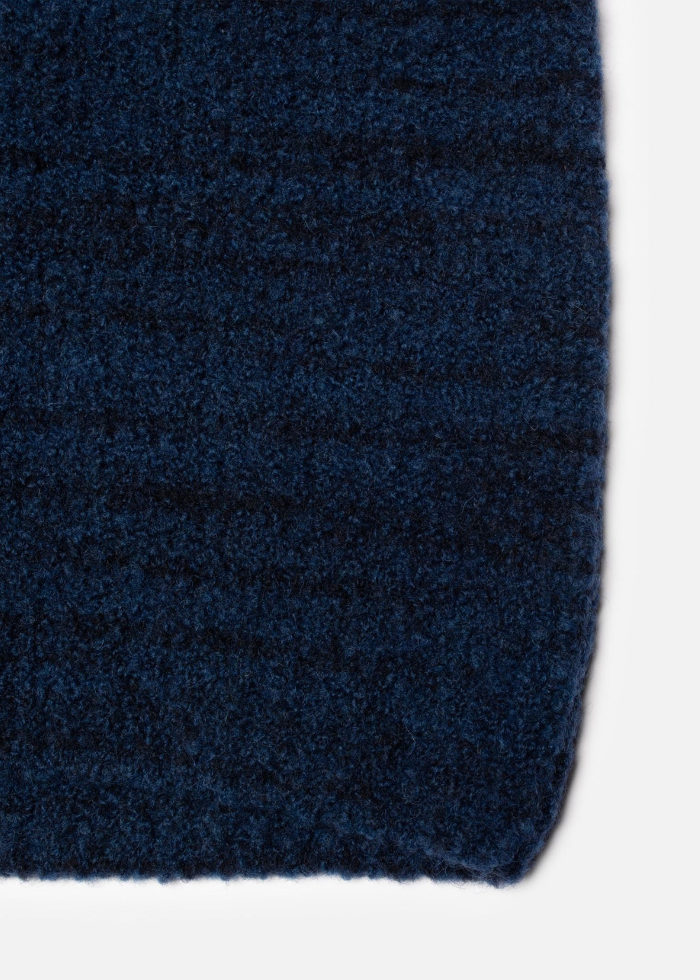 Close-up of a dark navy blue textured fabric, showing the knit or woven material and a folded edge against a light gray background.