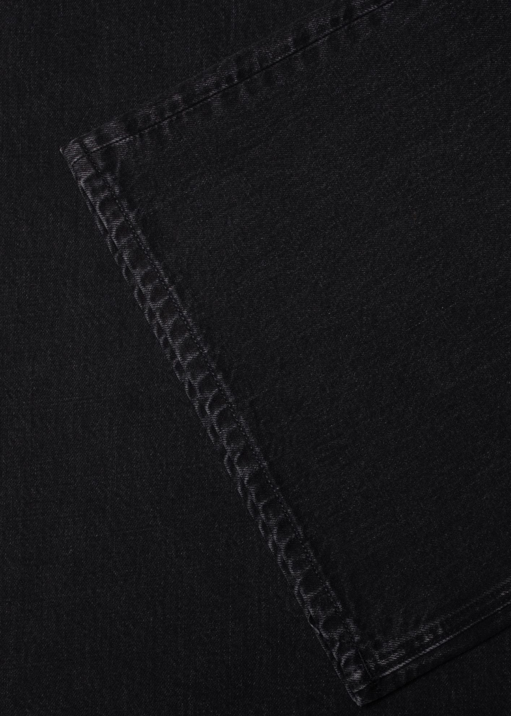 Close-up of a black denim fabric corner showing a double-stitched seam.