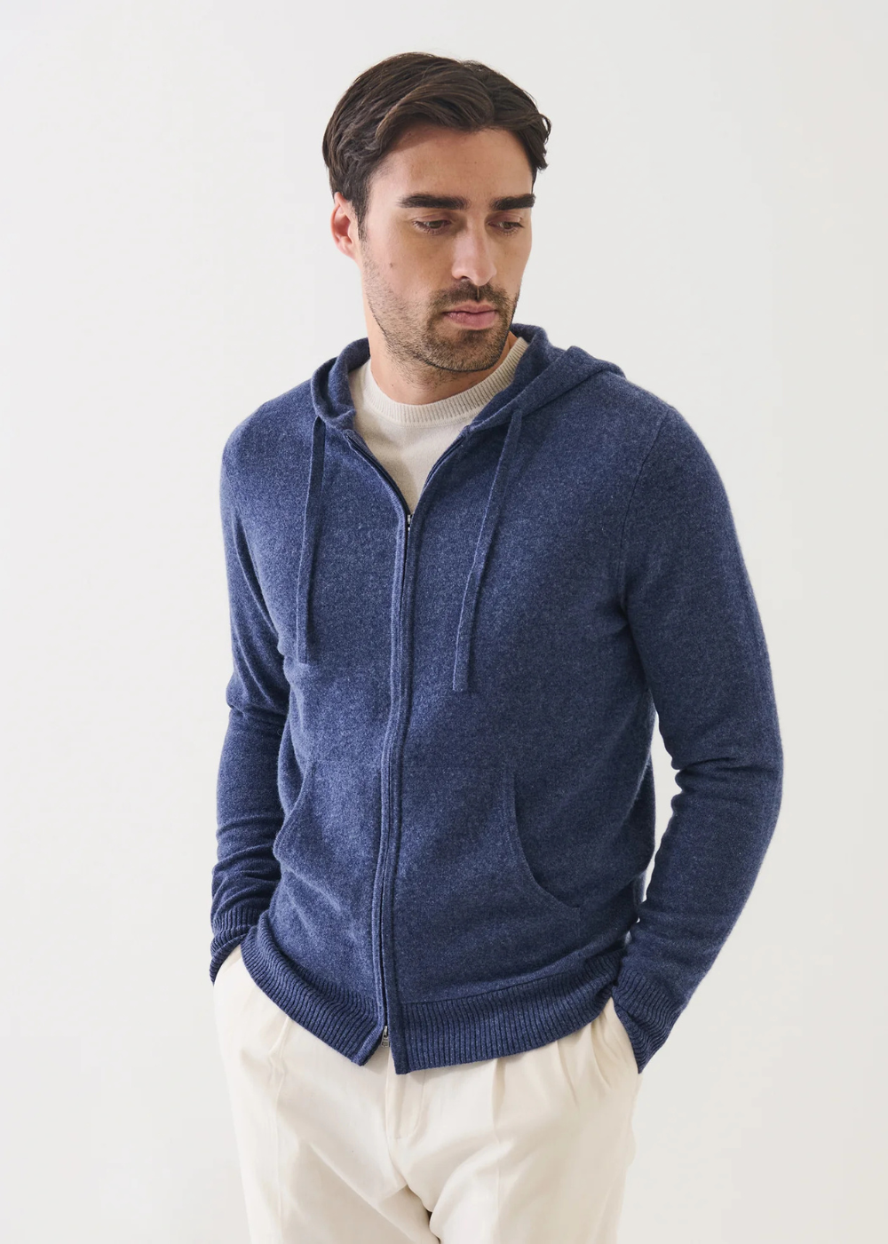 Man wearing a blue zip-up hoodie against a white background