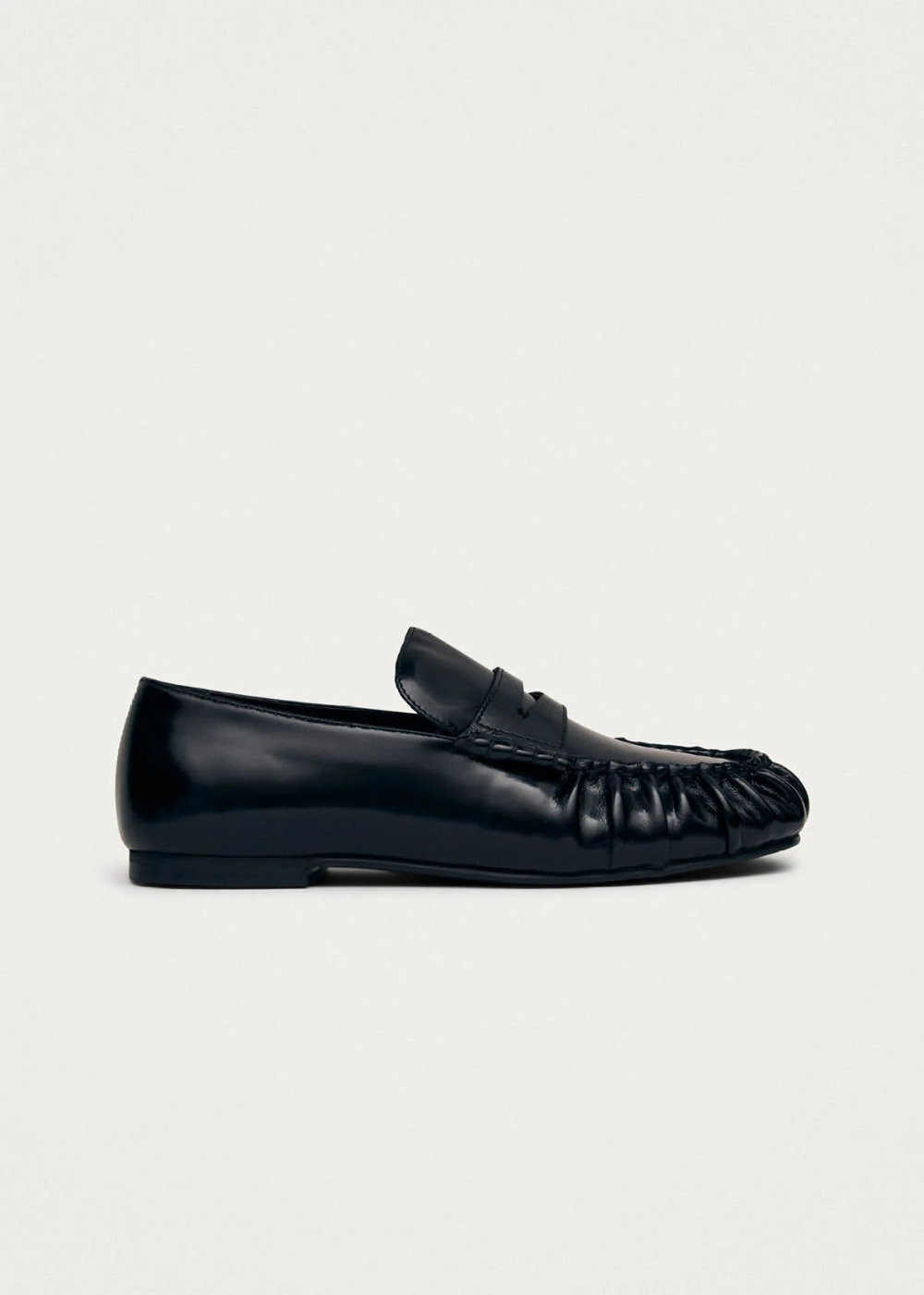 Black leather loafer set against a gray studio background