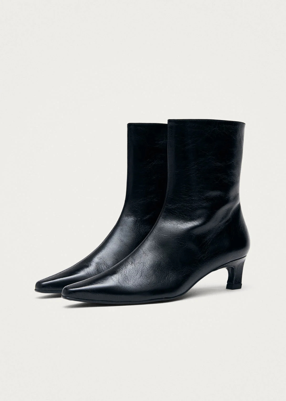 Pair of black leather ankle boots on a light gray background