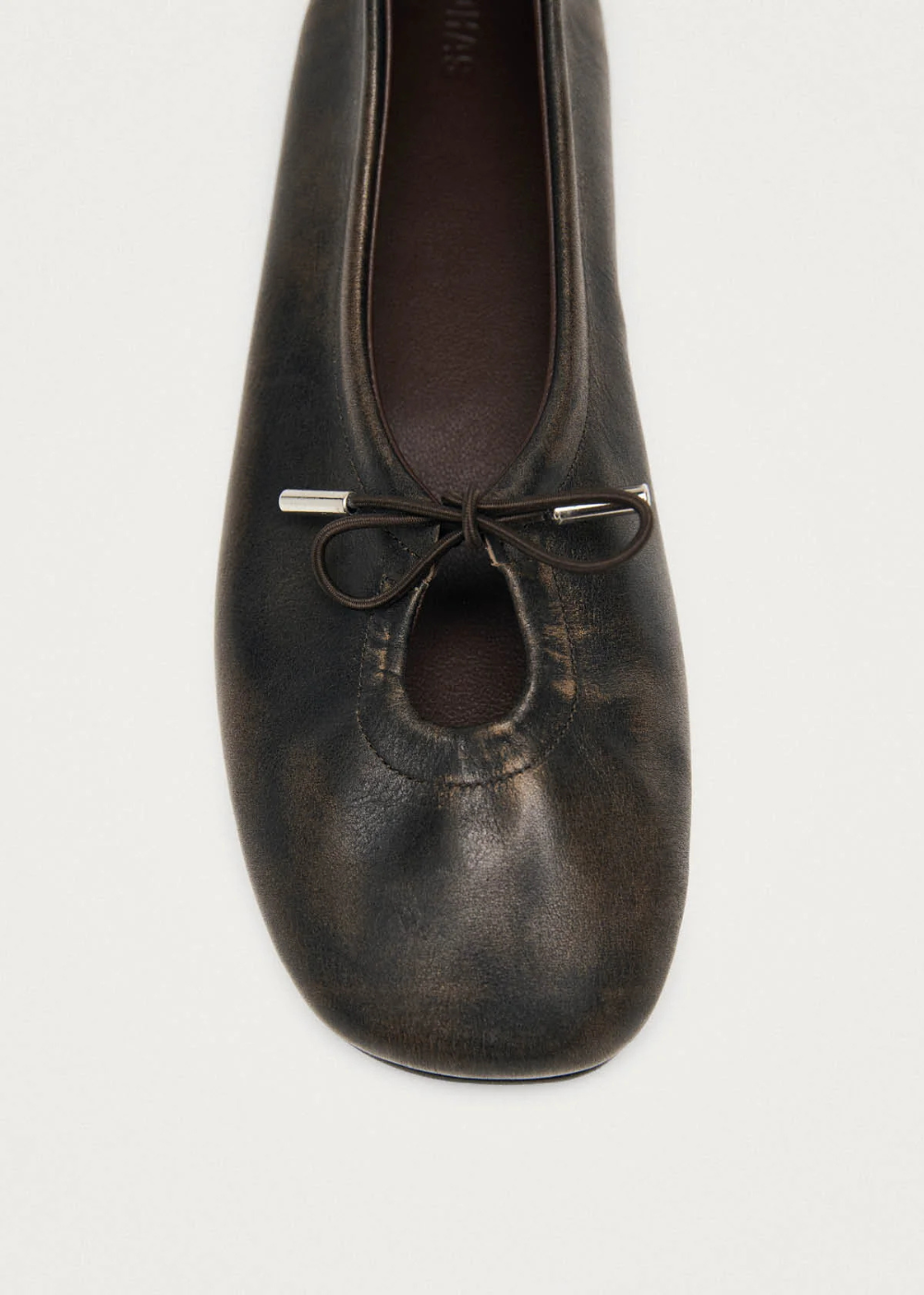 Brown leather ballet flat shoe with a bow on a white background