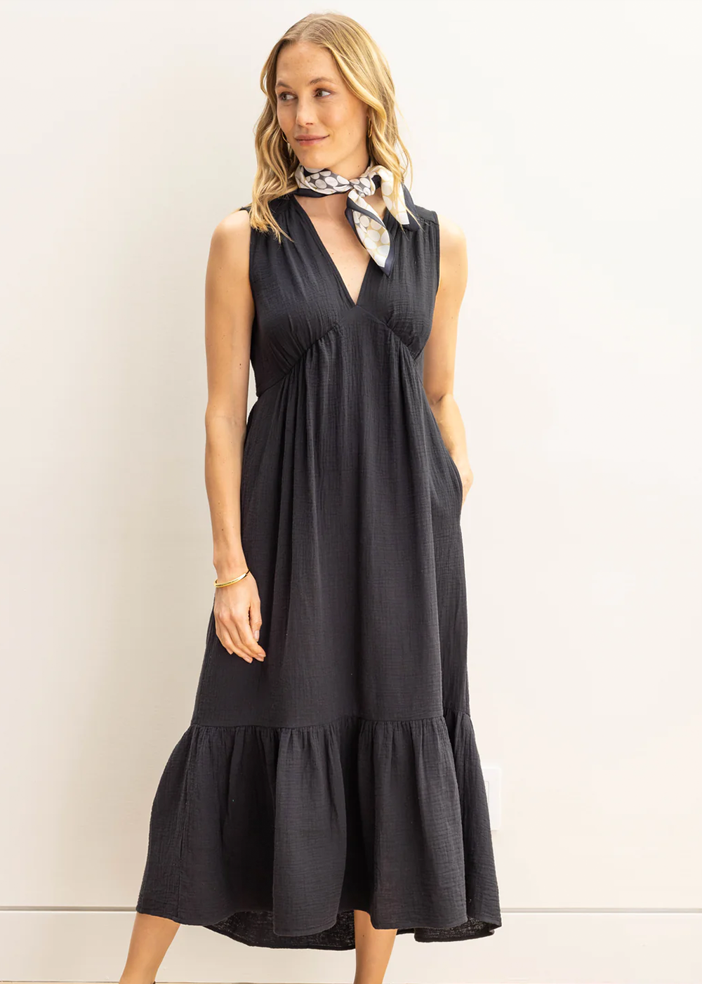 Female model wearing a black sleeveless maxi dress from Echo New York. Dress features super soft cotton, a relaxed fit with a modern silhouette. Length stops just above the ankles.